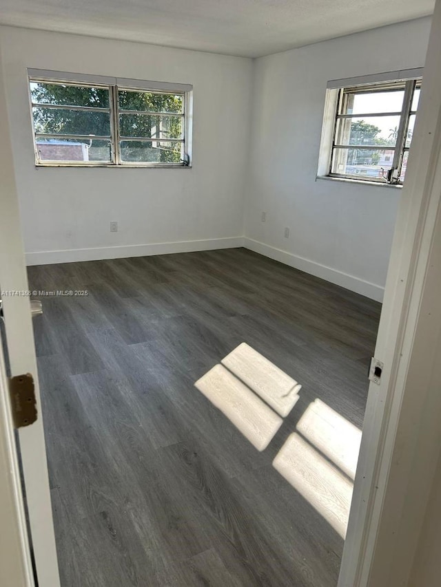 spare room with dark wood-type flooring and a healthy amount of sunlight