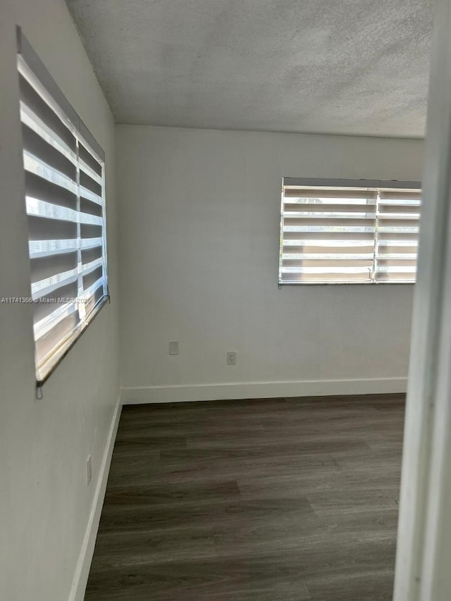 empty room with dark hardwood / wood-style flooring and a textured ceiling