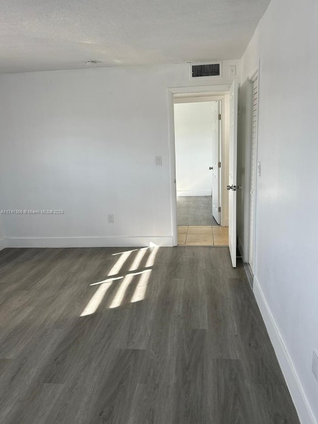 empty room with dark wood-type flooring and a textured ceiling