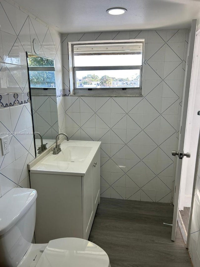 bathroom featuring vanity, hardwood / wood-style flooring, tile walls, and toilet