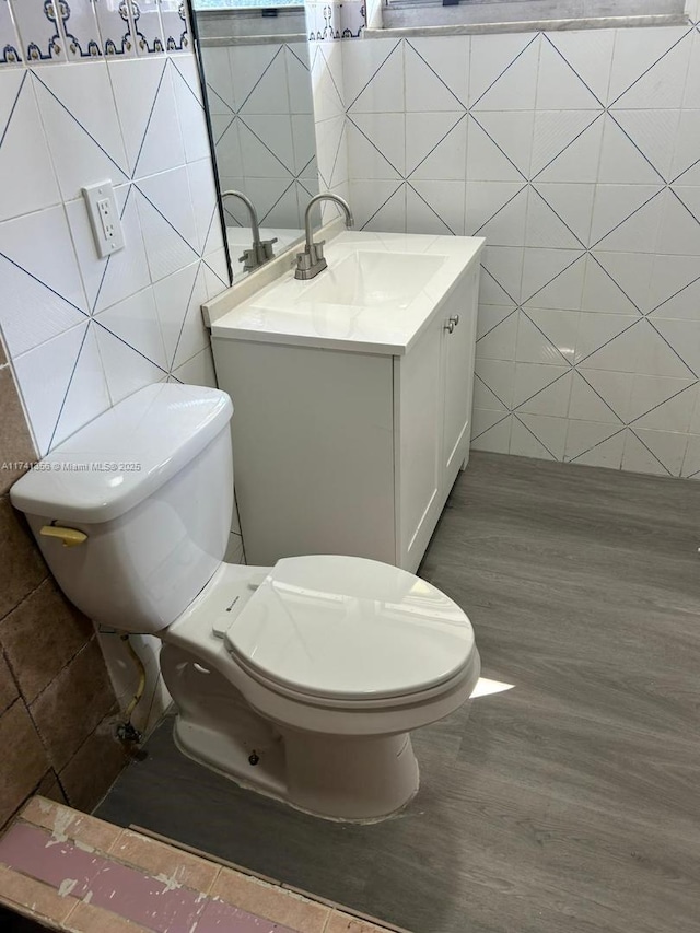 bathroom with vanity, hardwood / wood-style floors, tile walls, and toilet