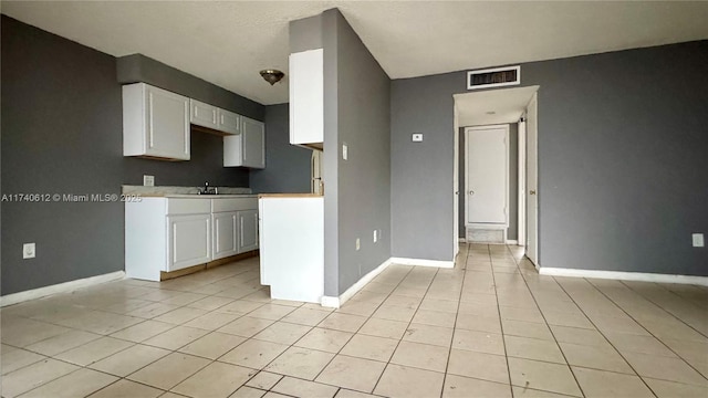 kitchen featuring light tile patterned flooring, sink, and white cabinets