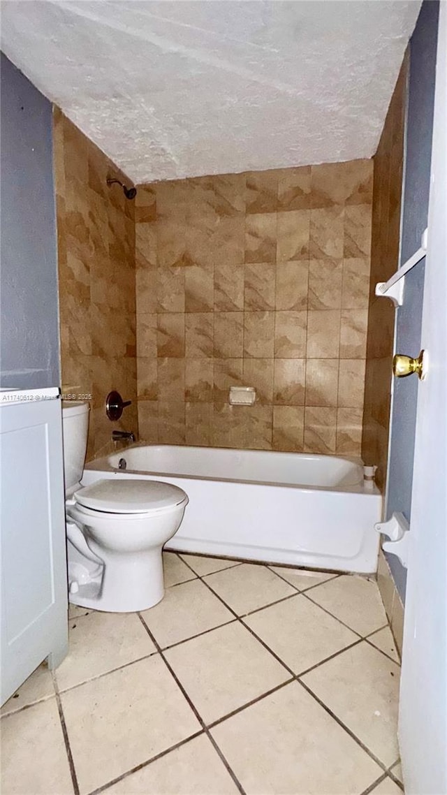 bathroom featuring tile patterned flooring, tiled shower / bath, a textured ceiling, and toilet