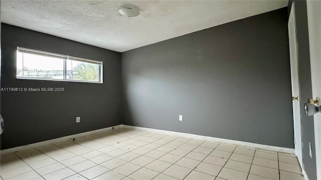 empty room featuring light tile patterned floors and a textured ceiling