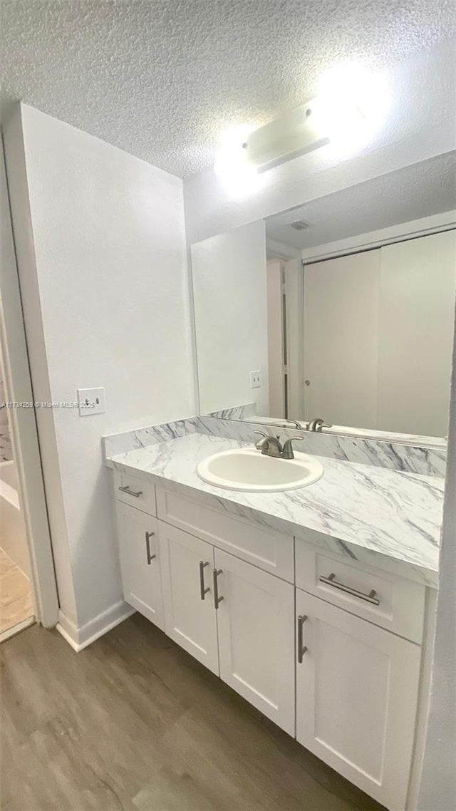 bathroom featuring vanity, hardwood / wood-style flooring, and a textured ceiling