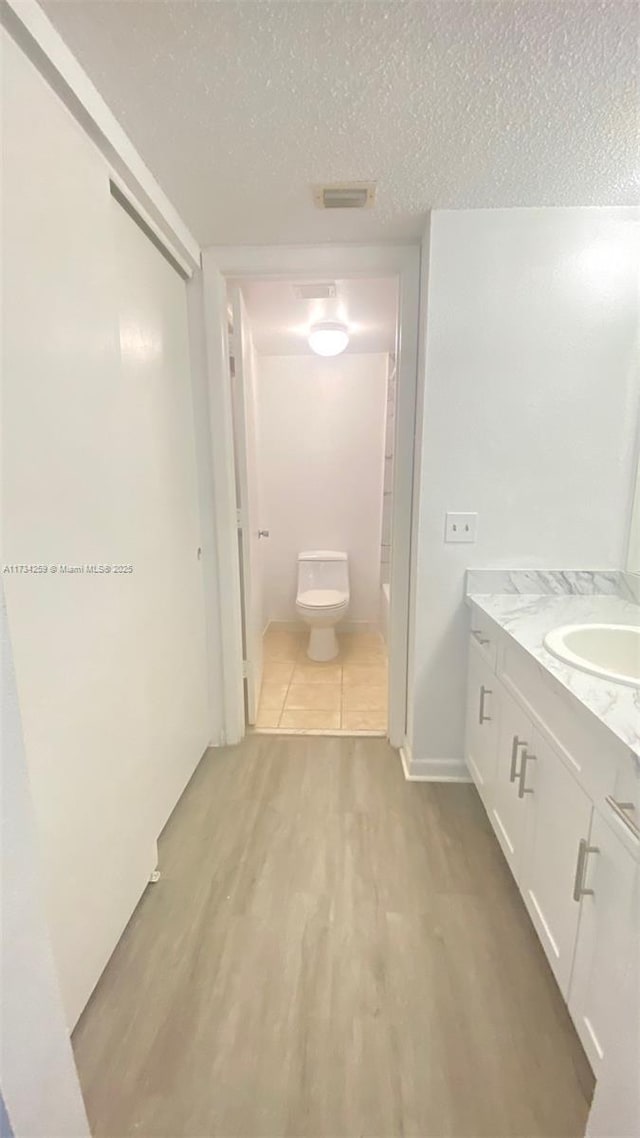 bathroom with vanity, hardwood / wood-style flooring, toilet, and a textured ceiling
