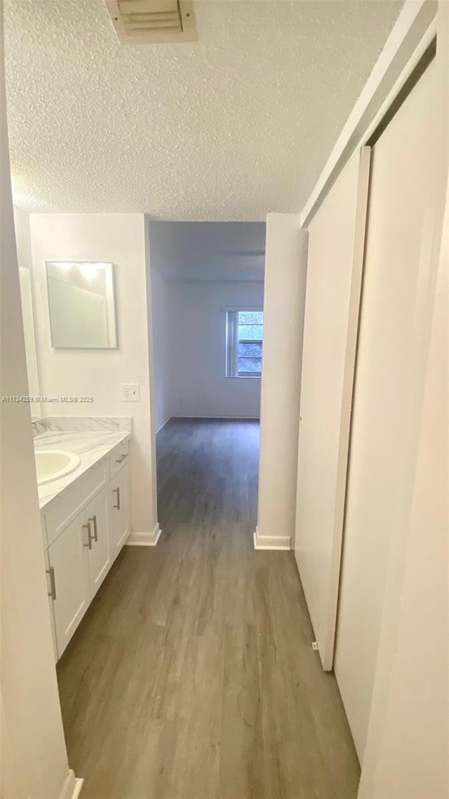 bathroom featuring hardwood / wood-style flooring, vanity, and a textured ceiling