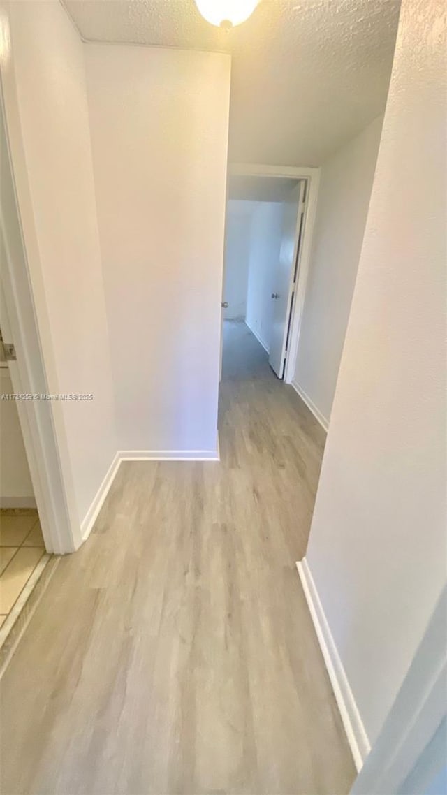 hall with light hardwood / wood-style floors and a textured ceiling