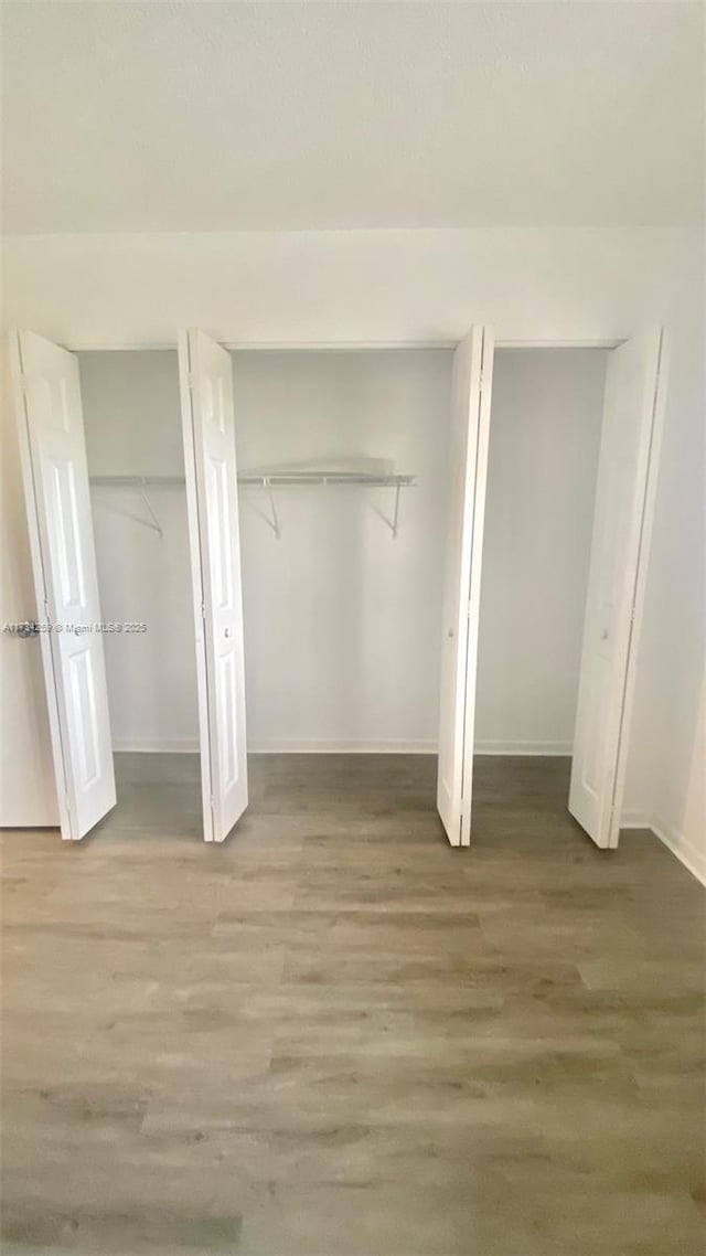 unfurnished bedroom with hardwood / wood-style flooring and multiple closets