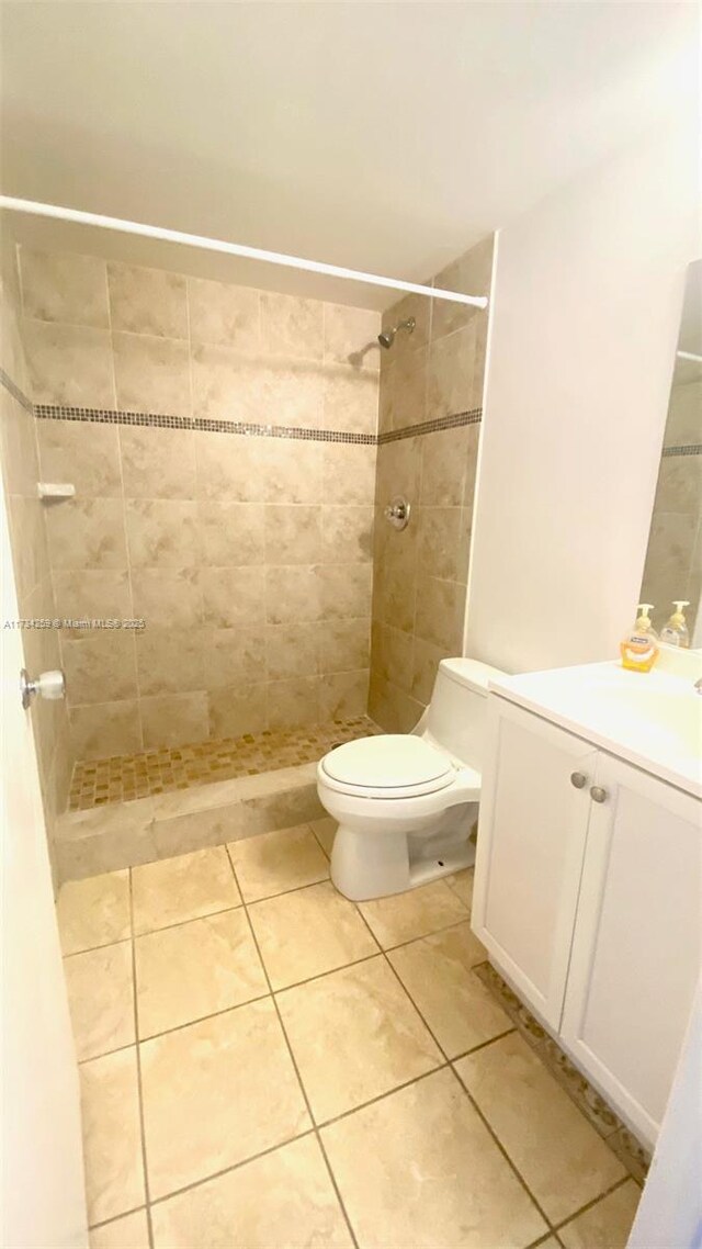 bathroom featuring tile patterned flooring, vanity, tiled shower, and toilet