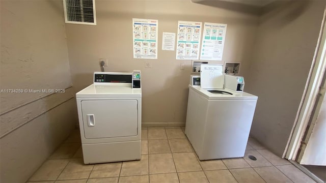 washroom with washing machine and clothes dryer and light tile patterned floors