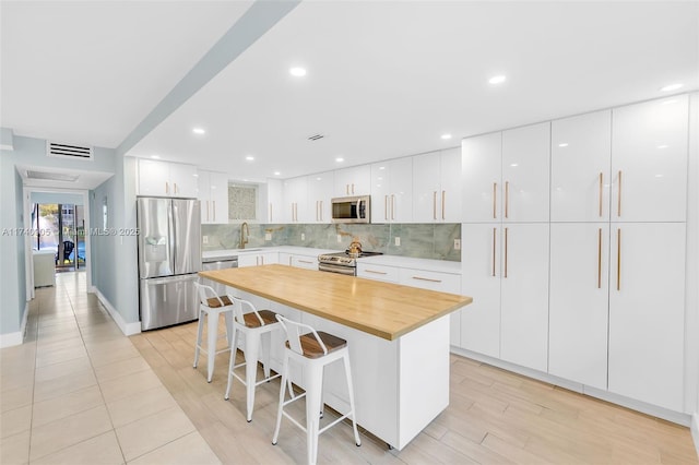 kitchen with stainless steel appliances, a center island, a breakfast bar, and white cabinets