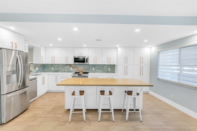 kitchen featuring a center island, stainless steel appliances, a breakfast bar, and white cabinets