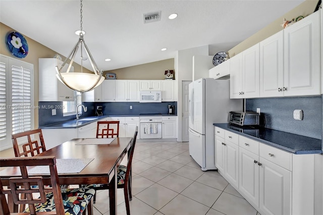 kitchen with vaulted ceiling, pendant lighting, white cabinetry, backsplash, and white appliances