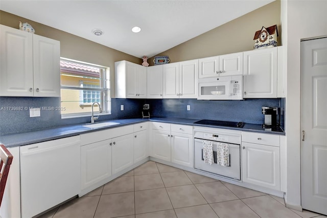 kitchen featuring lofted ceiling, sink, white appliances, white cabinetry, and backsplash