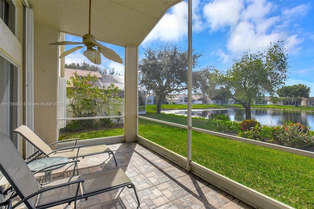 unfurnished sunroom with ceiling fan and a water view