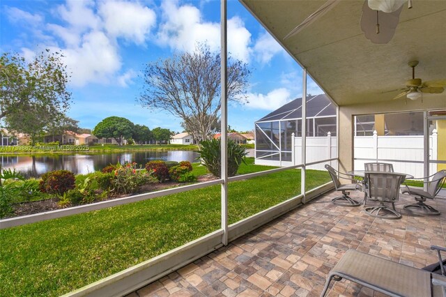 sunroom with ceiling fan and a water view