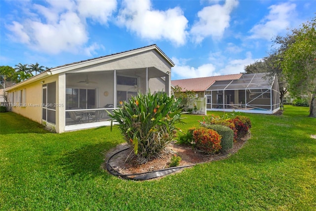 rear view of house featuring ceiling fan, a sunroom, and a lawn