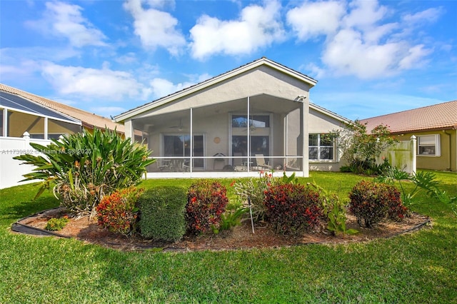 back of property with a sunroom and a lawn