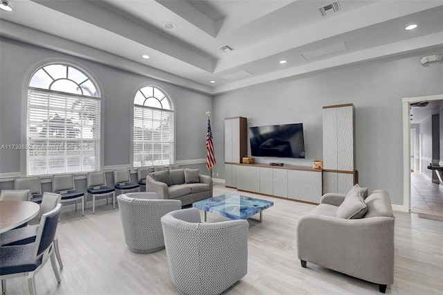 living room featuring a tray ceiling and light wood-type flooring