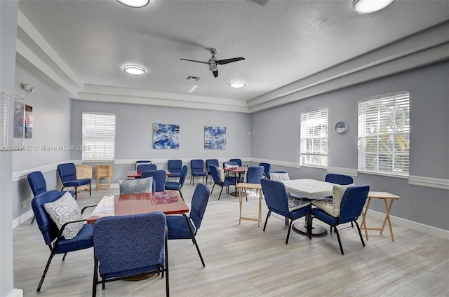 dining room with ceiling fan, plenty of natural light, a textured ceiling, and light hardwood / wood-style flooring