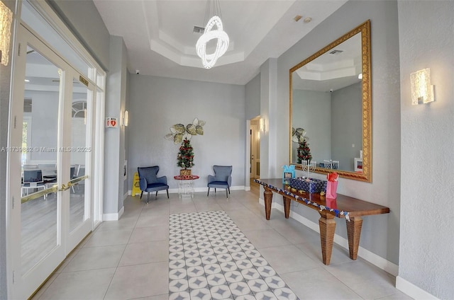 hallway with french doors, light tile patterned flooring, and a tray ceiling