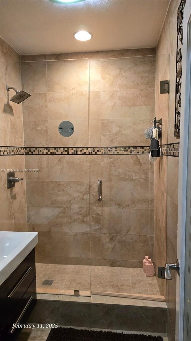 bathroom featuring vanity and a shower with door