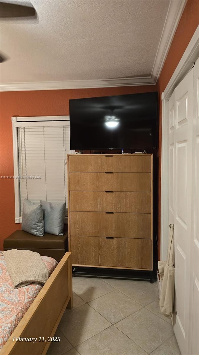 interior space with crown molding, a closet, a textured ceiling, and light tile patterned floors