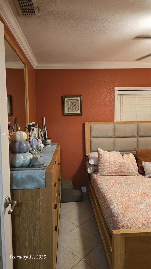 bedroom featuring ornamental molding, light tile patterned floors, and a textured ceiling