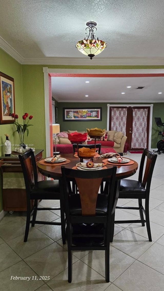 dining area with ornamental molding, tile patterned floors, and a textured ceiling