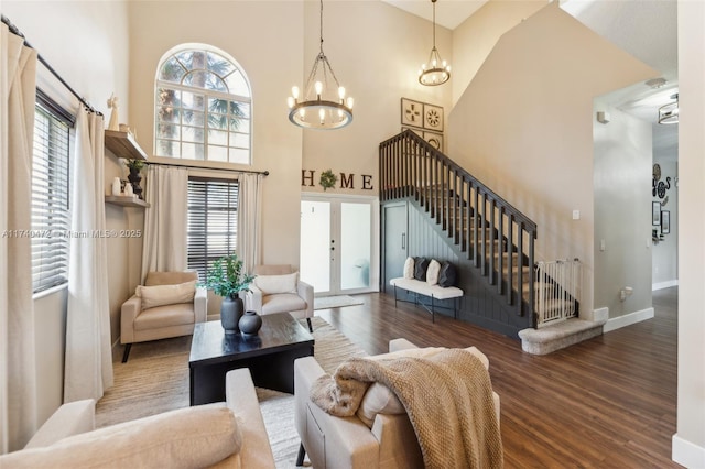 living room featuring dark hardwood / wood-style flooring, french doors, an inviting chandelier, and a high ceiling