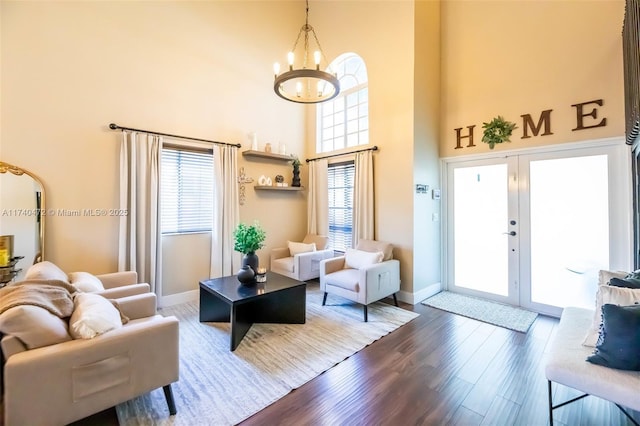 living room with an inviting chandelier, dark hardwood / wood-style flooring, french doors, and a high ceiling