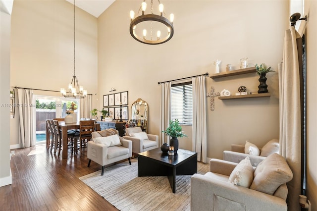 living room with a notable chandelier, hardwood / wood-style flooring, a wealth of natural light, and a towering ceiling