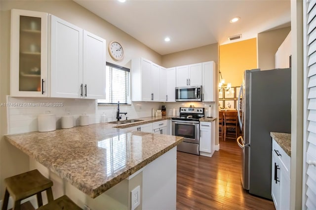 kitchen featuring sink, stainless steel appliances, tasteful backsplash, white cabinets, and kitchen peninsula