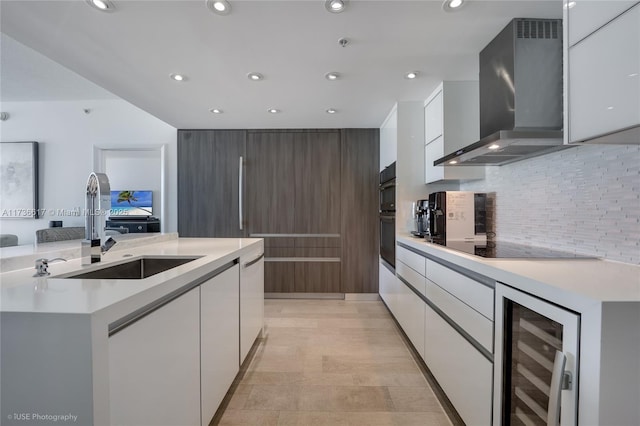 kitchen featuring wall chimney exhaust hood, sink, white cabinetry, a center island, and beverage cooler