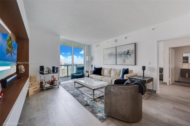 living room with floor to ceiling windows, wood-type flooring, and a textured ceiling