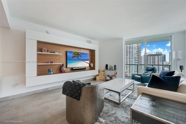 living room featuring light hardwood / wood-style flooring, expansive windows, and a textured ceiling