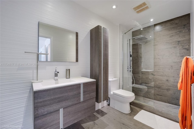 bathroom with tiled shower, vanity, and toilet