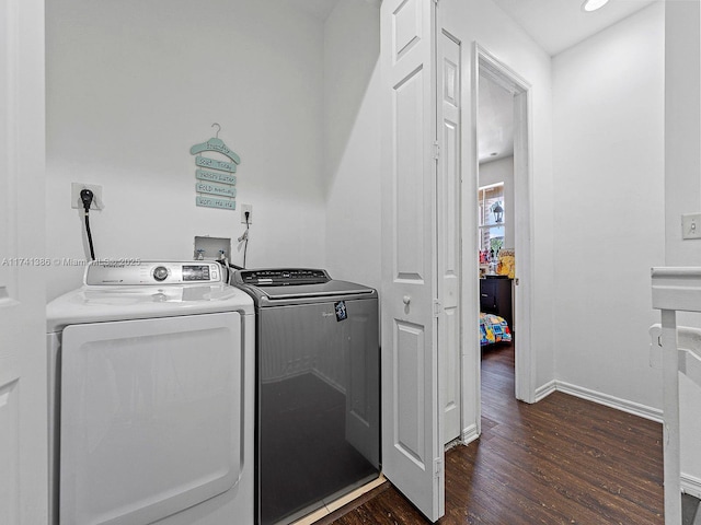 clothes washing area featuring laundry area, baseboards, dark wood-style flooring, and washer and clothes dryer