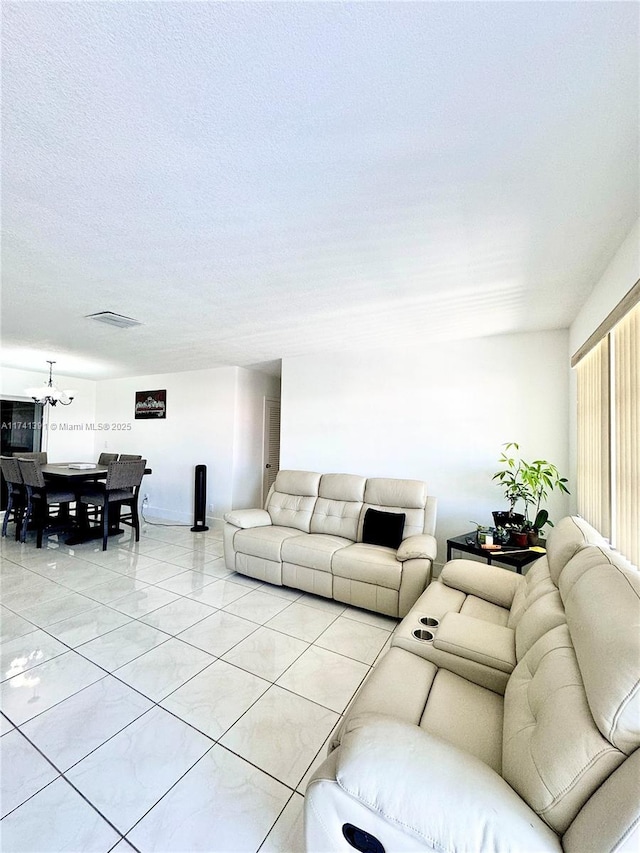 living room featuring light tile patterned floors, a notable chandelier, and a textured ceiling