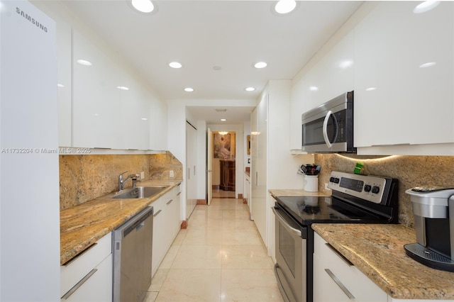 kitchen with stainless steel appliances, light stone countertops, sink, and white cabinets