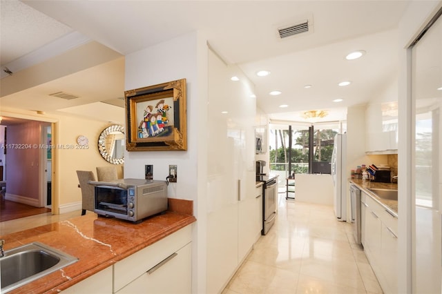 kitchen featuring light tile patterned floors, stainless steel appliances, sink, and white cabinets