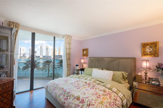 bedroom featuring dark wood-type flooring, access to exterior, floor to ceiling windows, ornamental molding, and a textured ceiling