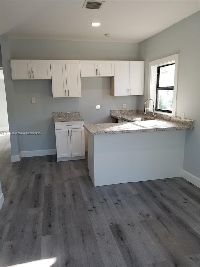 kitchen featuring sink, hardwood / wood-style floors, white cabinets, and kitchen peninsula