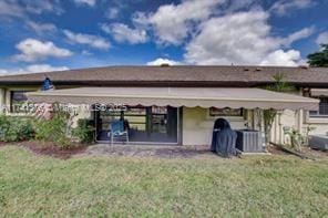 rear view of property with a yard and central AC unit