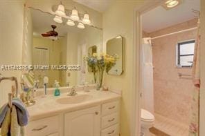 bathroom with vanity, curtained shower, ceiling fan, and toilet