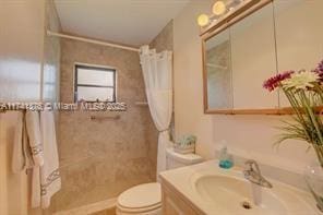 bathroom with walk in shower, vanity, and toilet