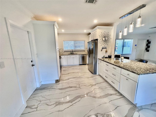 kitchen featuring white cabinetry, appliances with stainless steel finishes, sink, and hanging light fixtures