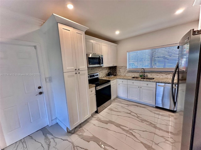 kitchen with sink, white cabinetry, backsplash, stainless steel appliances, and light stone countertops