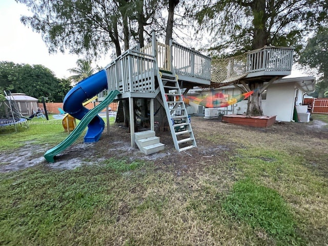 view of play area with a trampoline, central air condition unit, and a lawn